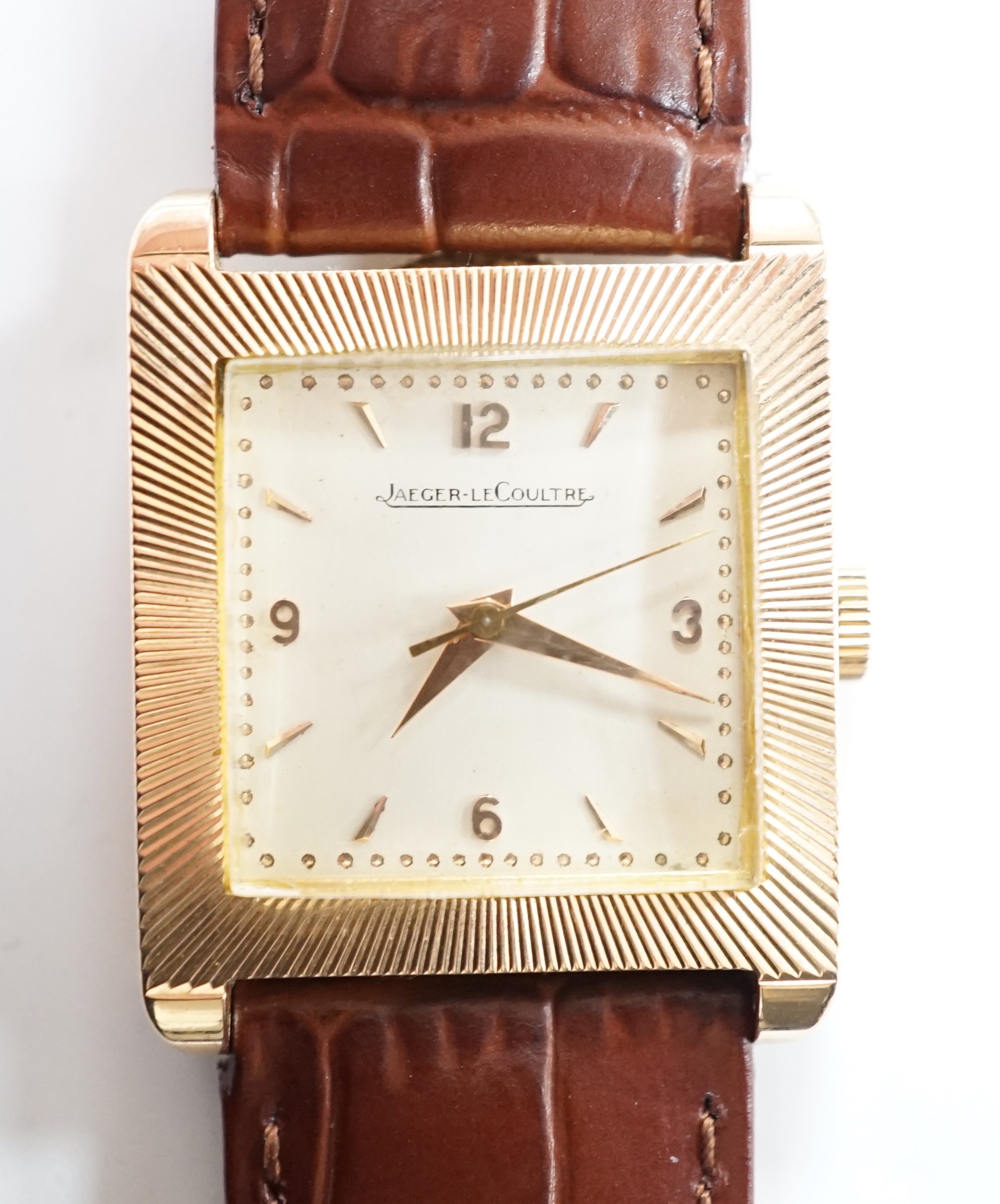 A gentleman's 18ct gold Jaeger LeCoultre manual wind dress wrist watch, with square dial, milled bezel and baton and quarterly Arabic numerals, on associated leather strap, case diameter 26mm, gross weight 31.8 grams.